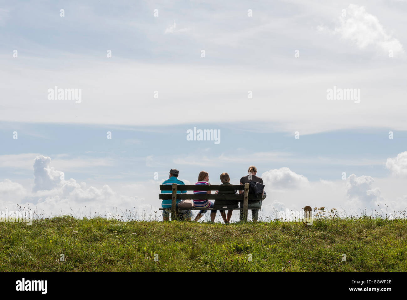 A family resting on a bench on a dike at Oudeschild, a small village on the isle of Texel. Stock Photo