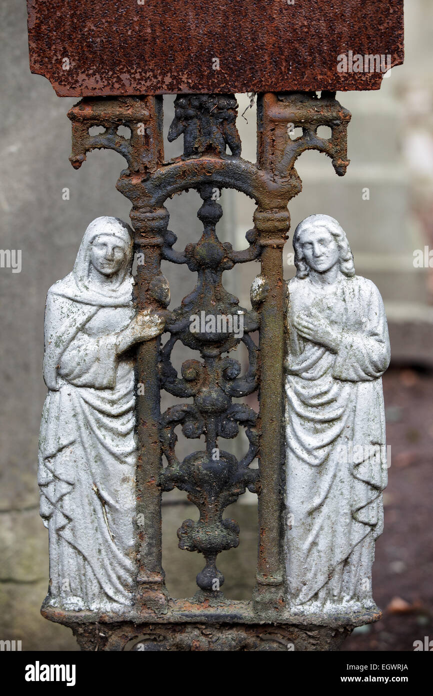 Detail of a old iron cross at the cemetery Hasselt Color, 2 saints holding the crucifix Stock Photo