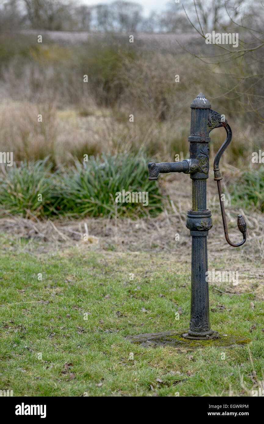 Old, hand-operated, reciprocating, positive displacement, cast iron cast-iron water pump in a Yorkshire field. Stock Photo