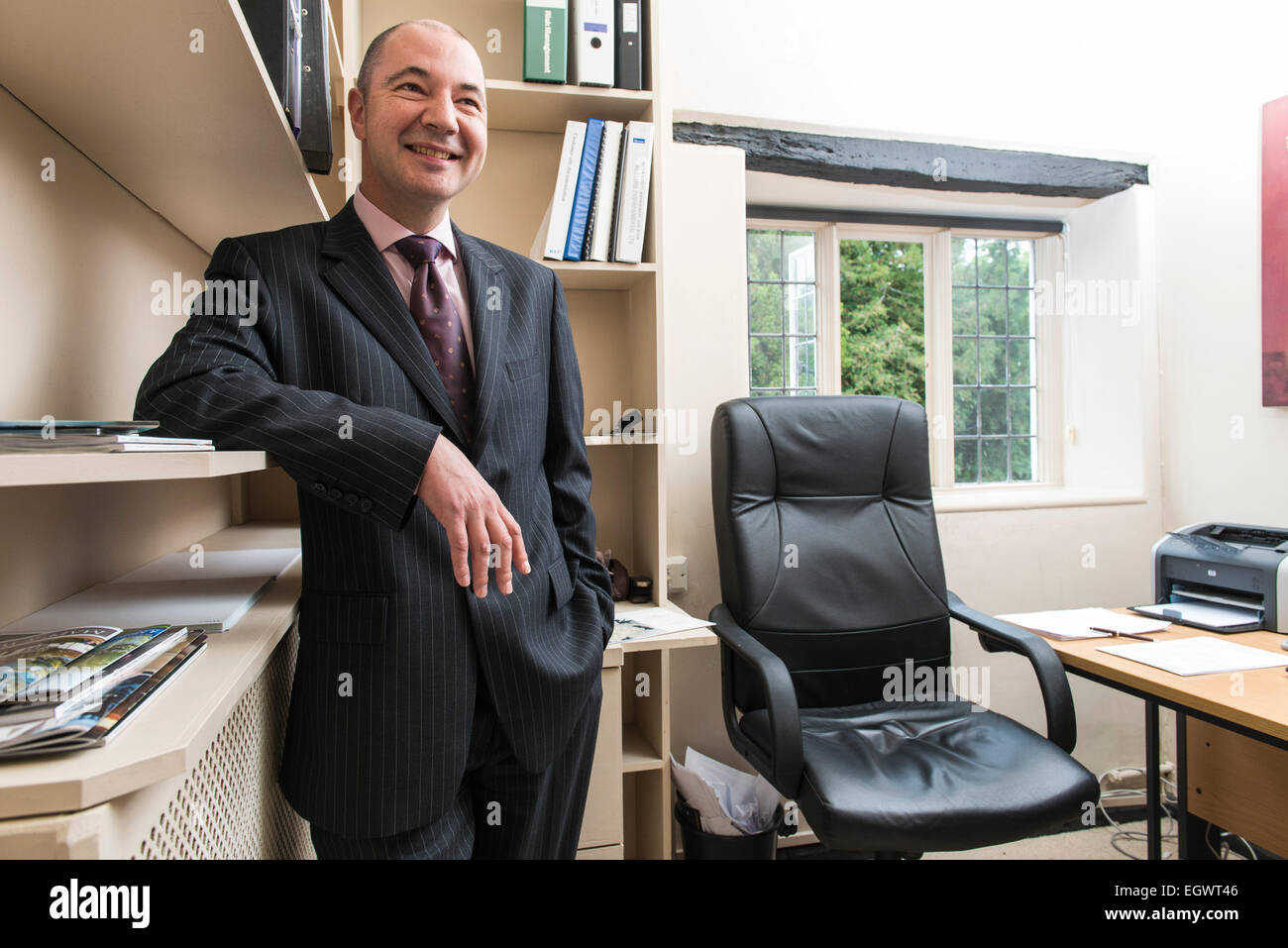 a professional businessman manager in his business suit stands in his small office of an english country house hotel Stock Photo