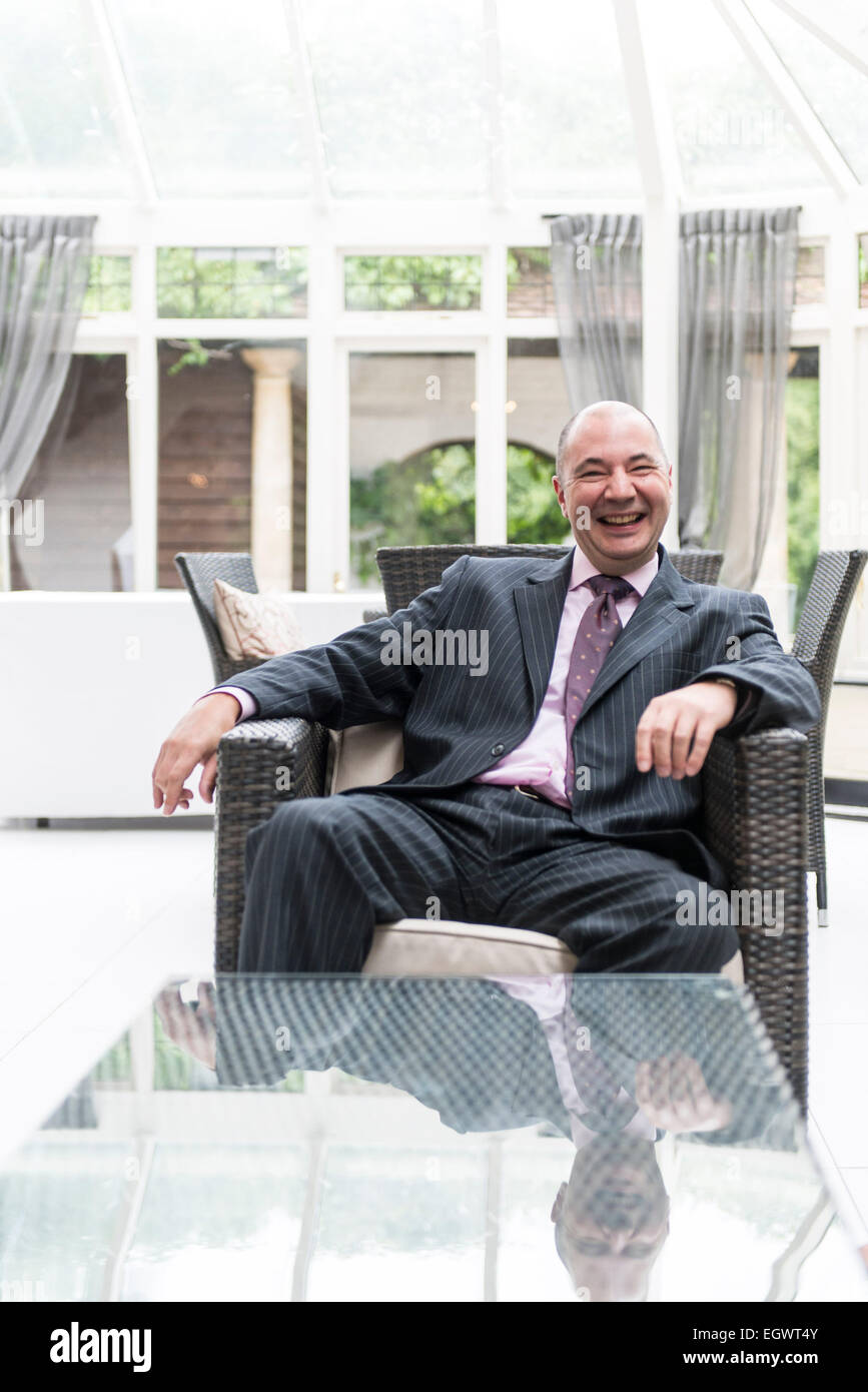 a relaxed professional businessman office manager sits in an armchair at a country house hotel