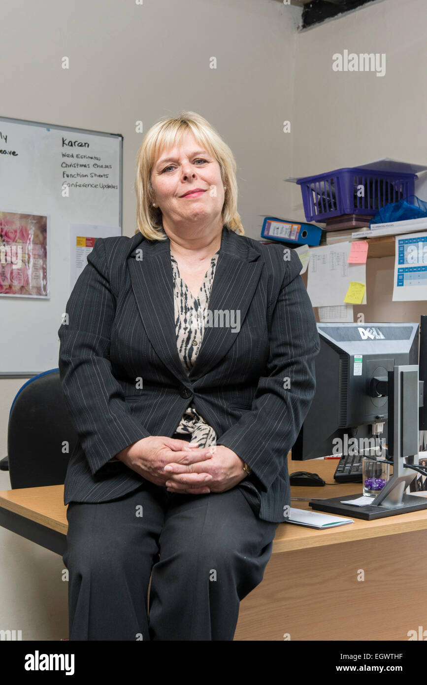 a business administrator office manager by her desk in a busy office