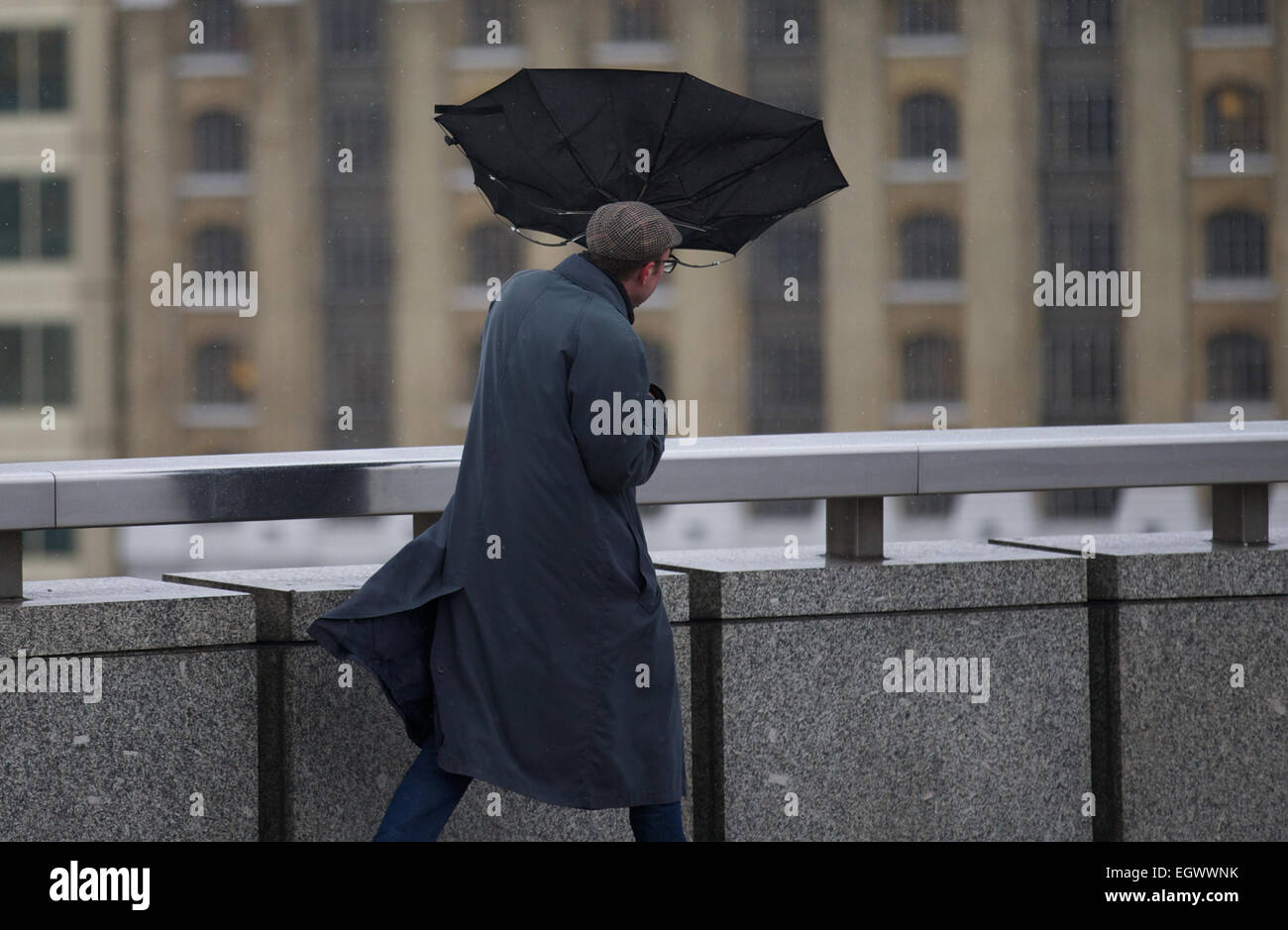 UNITED KINGDOM, London : A man battles the high winds with her umbrella as he walks across a bridge in central London on February 12, 2014. Stock Photo