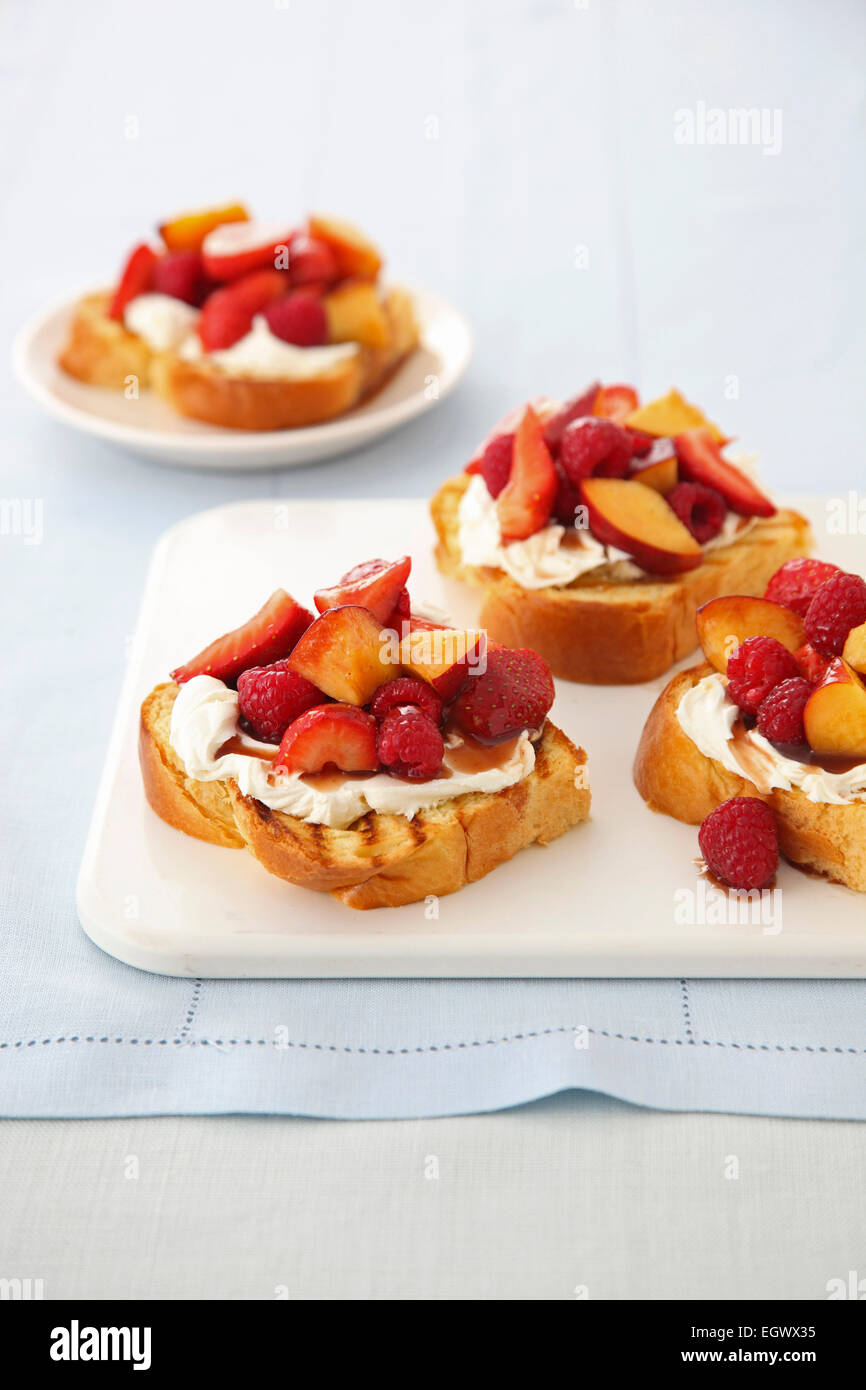 Fruit bruschetta, toast topped with cream, raspberries and peaches Stock Photo