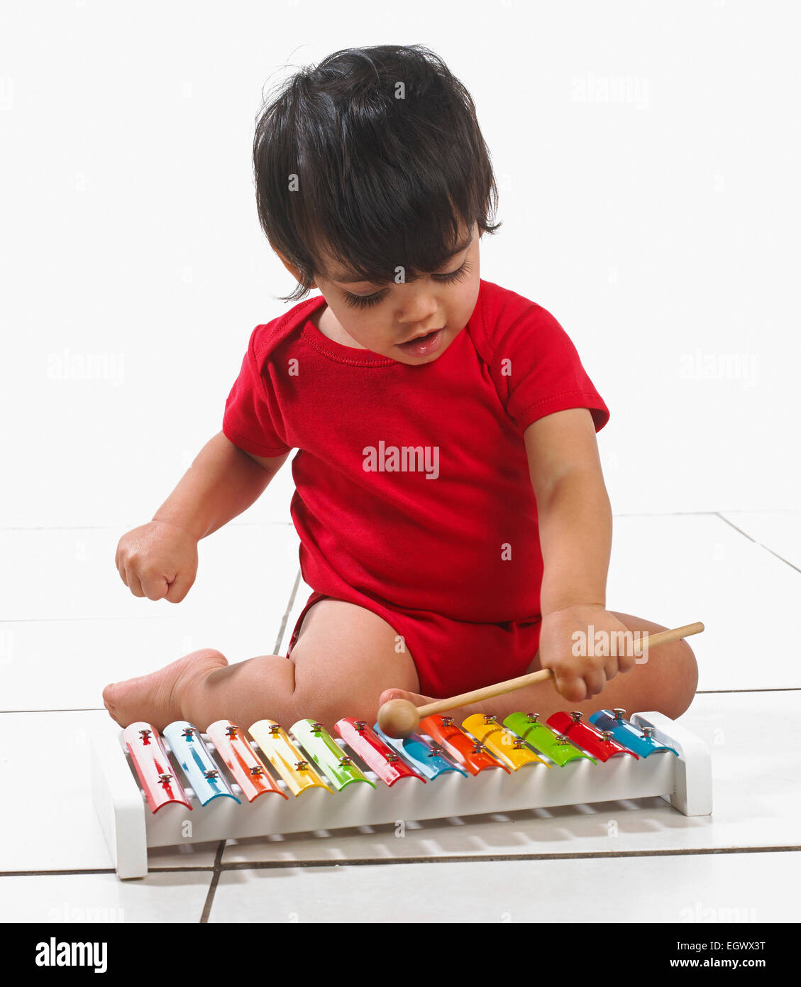 Small boy (16 months) sitting playing colourful xylophone Stock Photo
