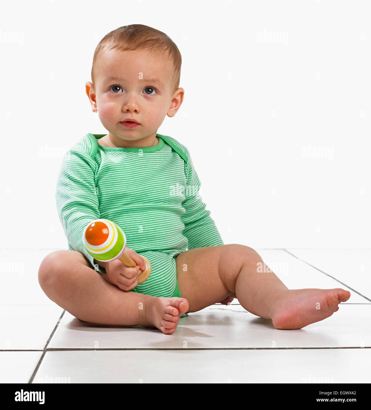 Baby boy (12.5 months) sitting playing with a maraca Stock Photo