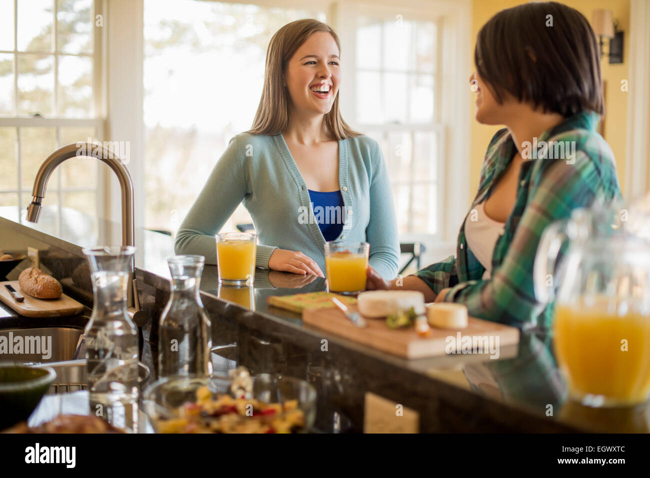 Two women seated at a kitchen counter, talking. Stock Photo