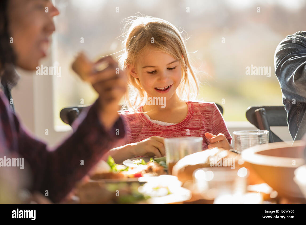A group of people, adults and children, seated around a table for a meal. Stock Photo