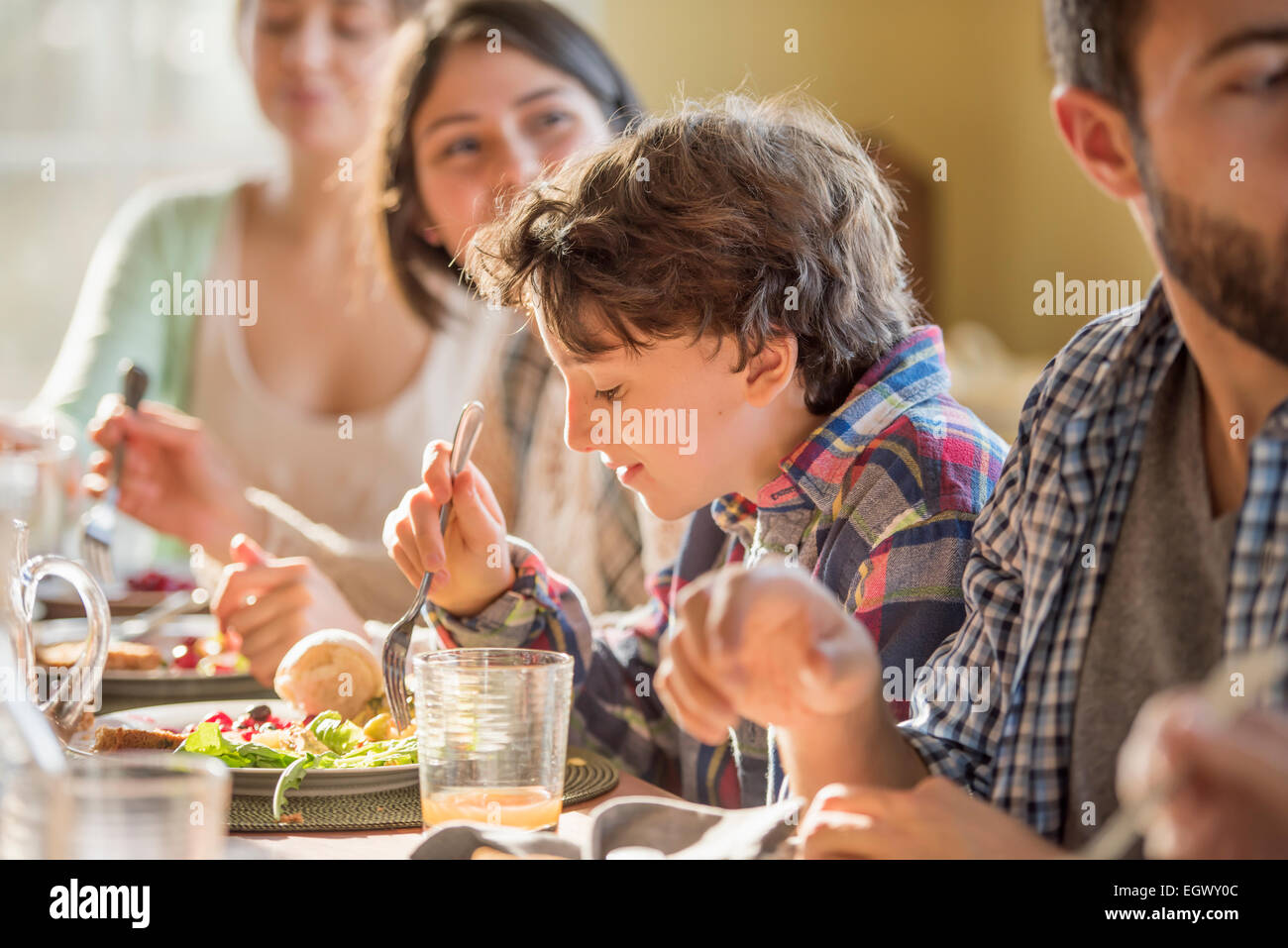 A group of people, adults and children, seated around a table for a meal. Stock Photo