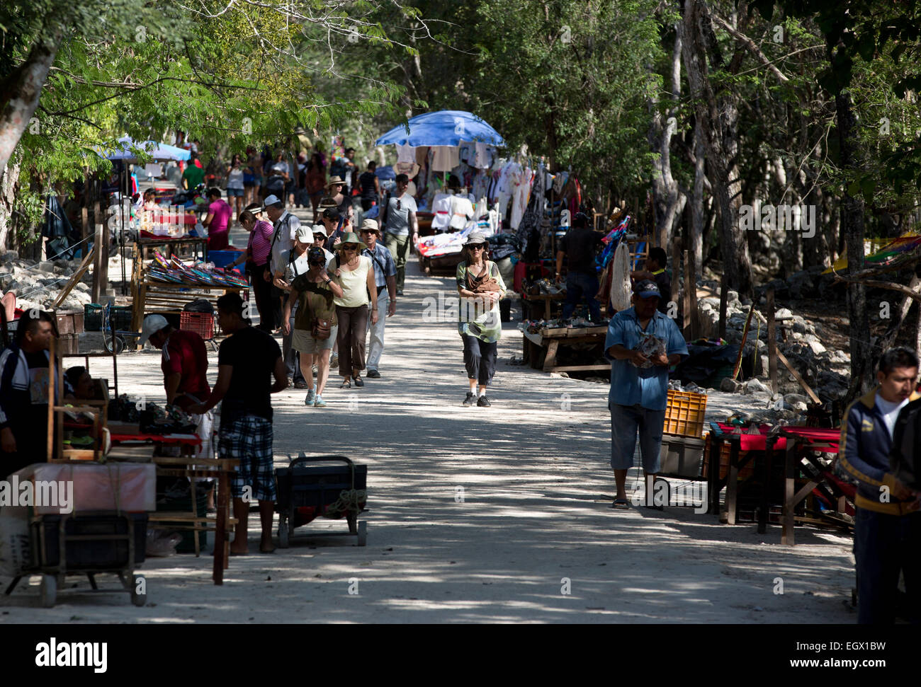 Tourists walk along a path lined with souvenir vendors at the Mayan