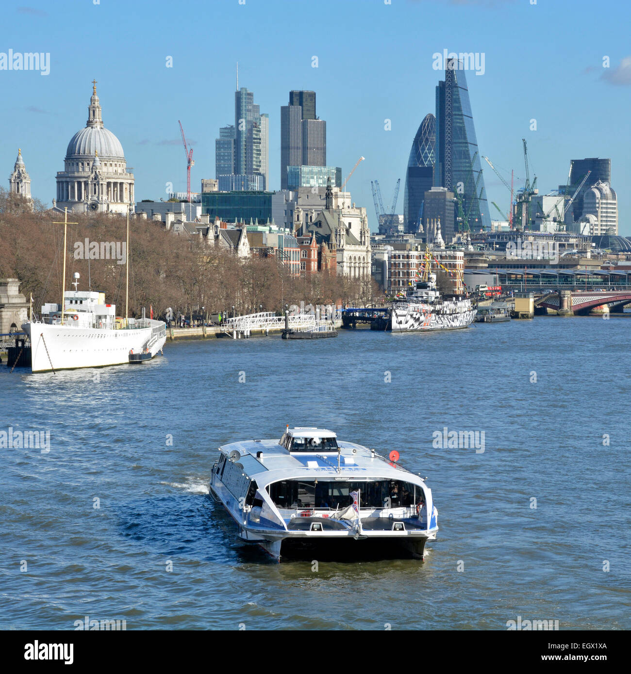 Thames clipper high speed catamaran commuter and tourist river bus service with City of London skyline beyond England UK Stock Photo