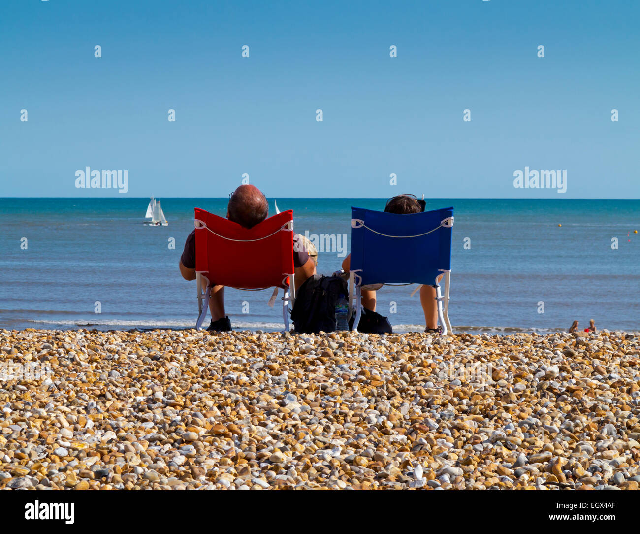 Couple relaxing on the beach in summer at Lyme Regis a seaside resort ...