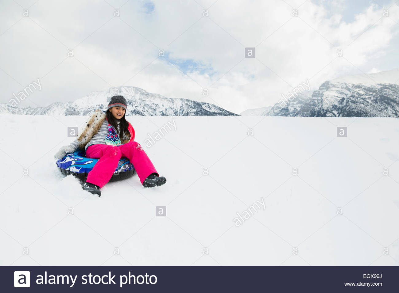 Girl riding inner tube down snowy hill Stock Photo - Alamy