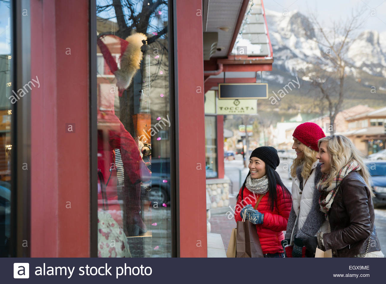 Women in warm clothing window shopping at storefront Stock Photo