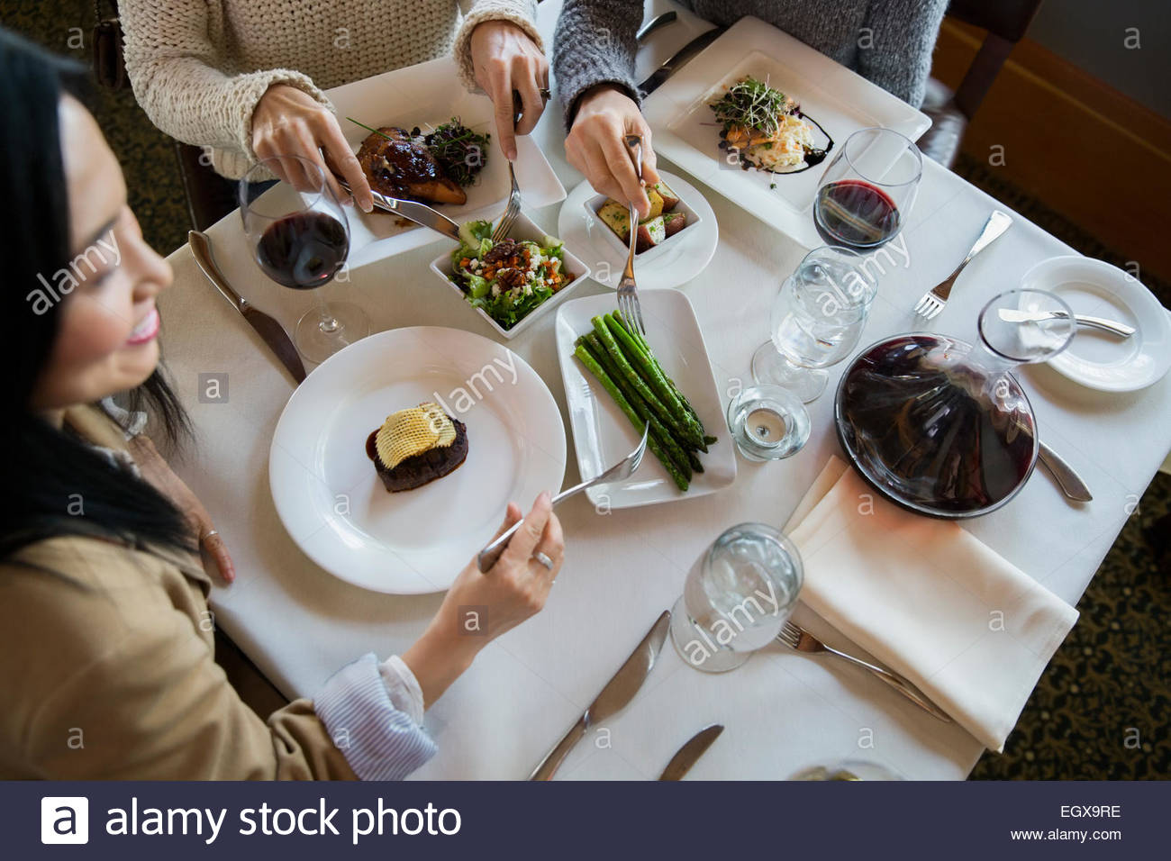 Women sharing asparagus at restaurant table Stock Photo
