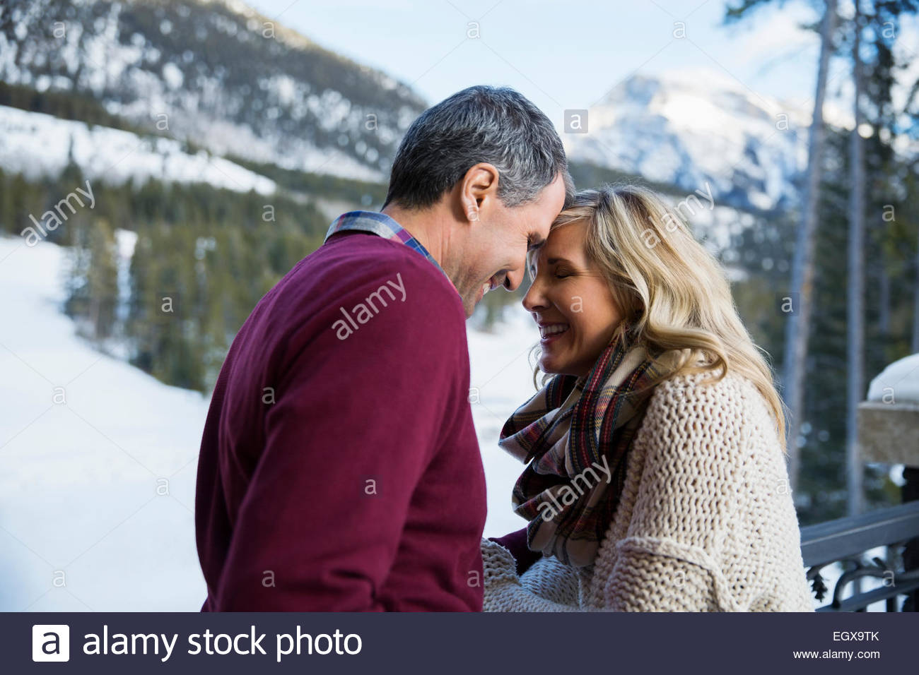 Affectionate couple on deck below snowy mountains Stock Photo Alamy