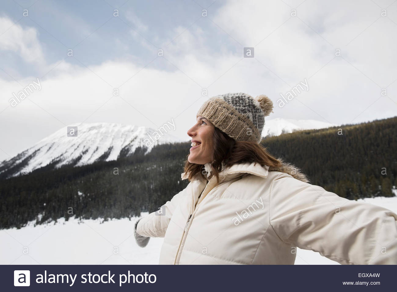 Smiling woman with arms outstretched in snowy field Stock Photo