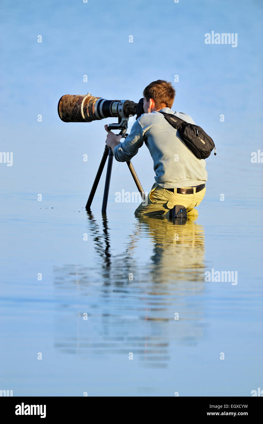 Photographer using a telephoto lens for wading birds in a shallow