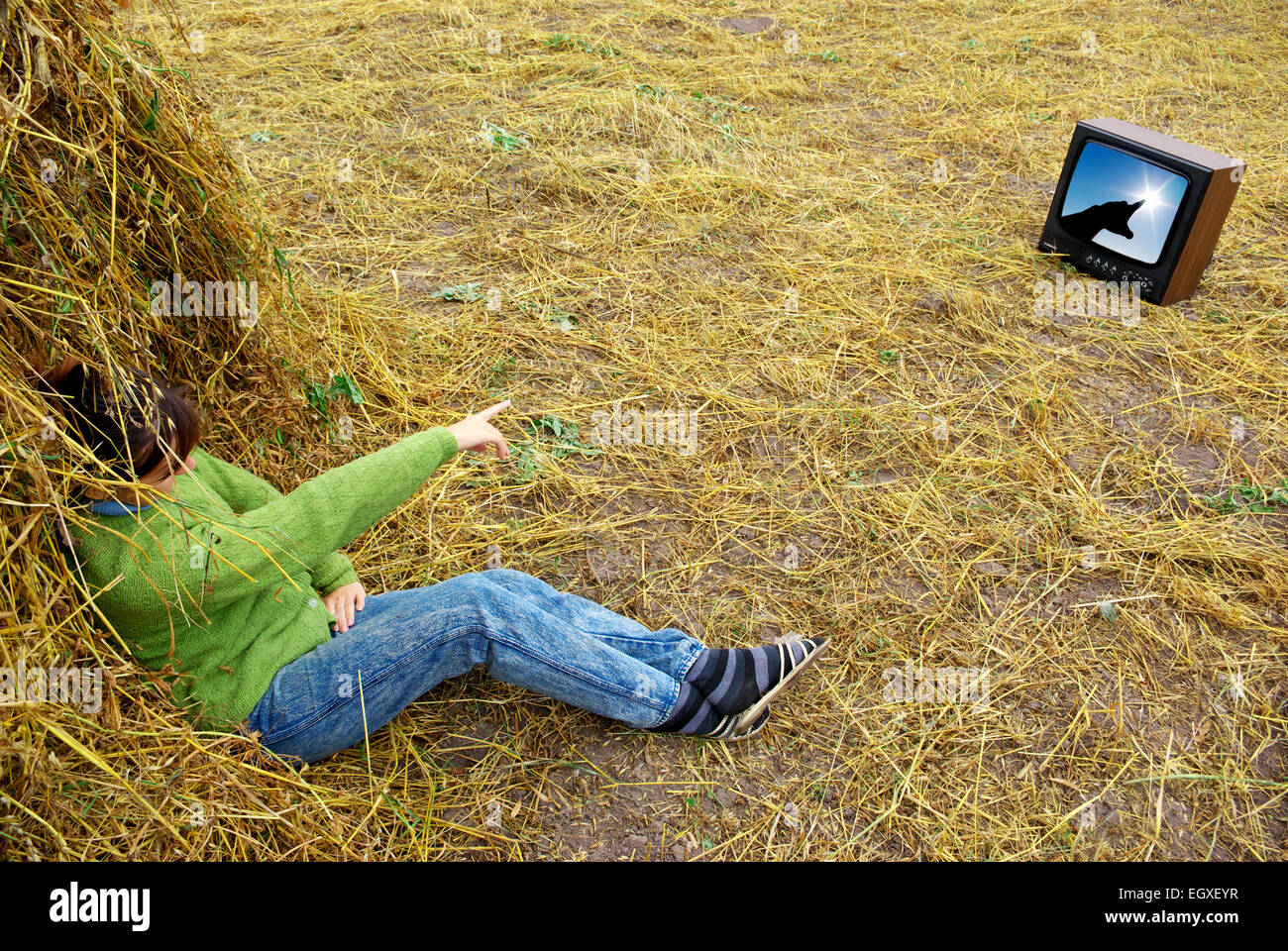 Girl on hay watch tv. Conceptual design. Stock Photo