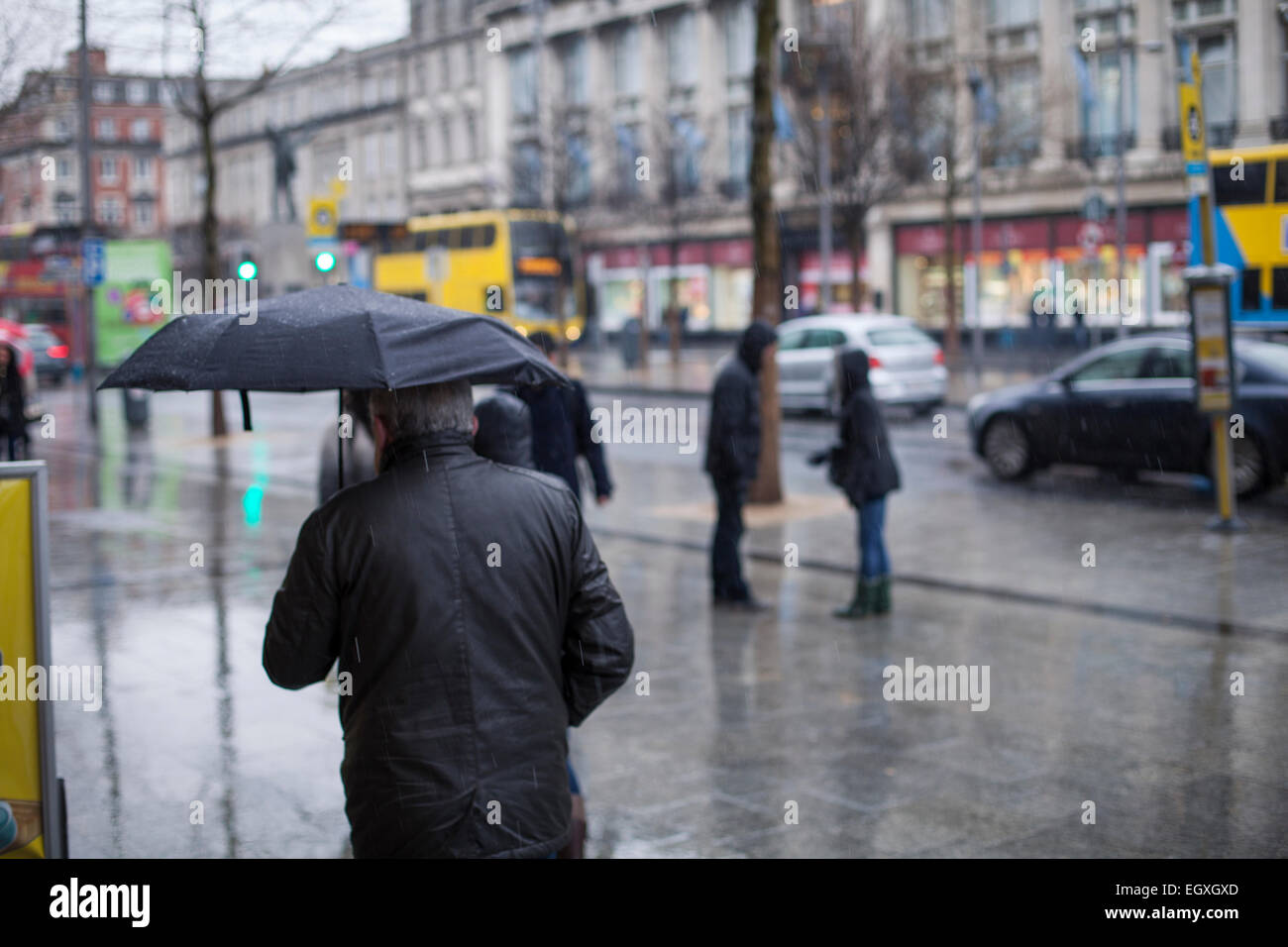 Man with umbrella on Dublin's O'Connell street in the rain on a Sunday Stock Photo