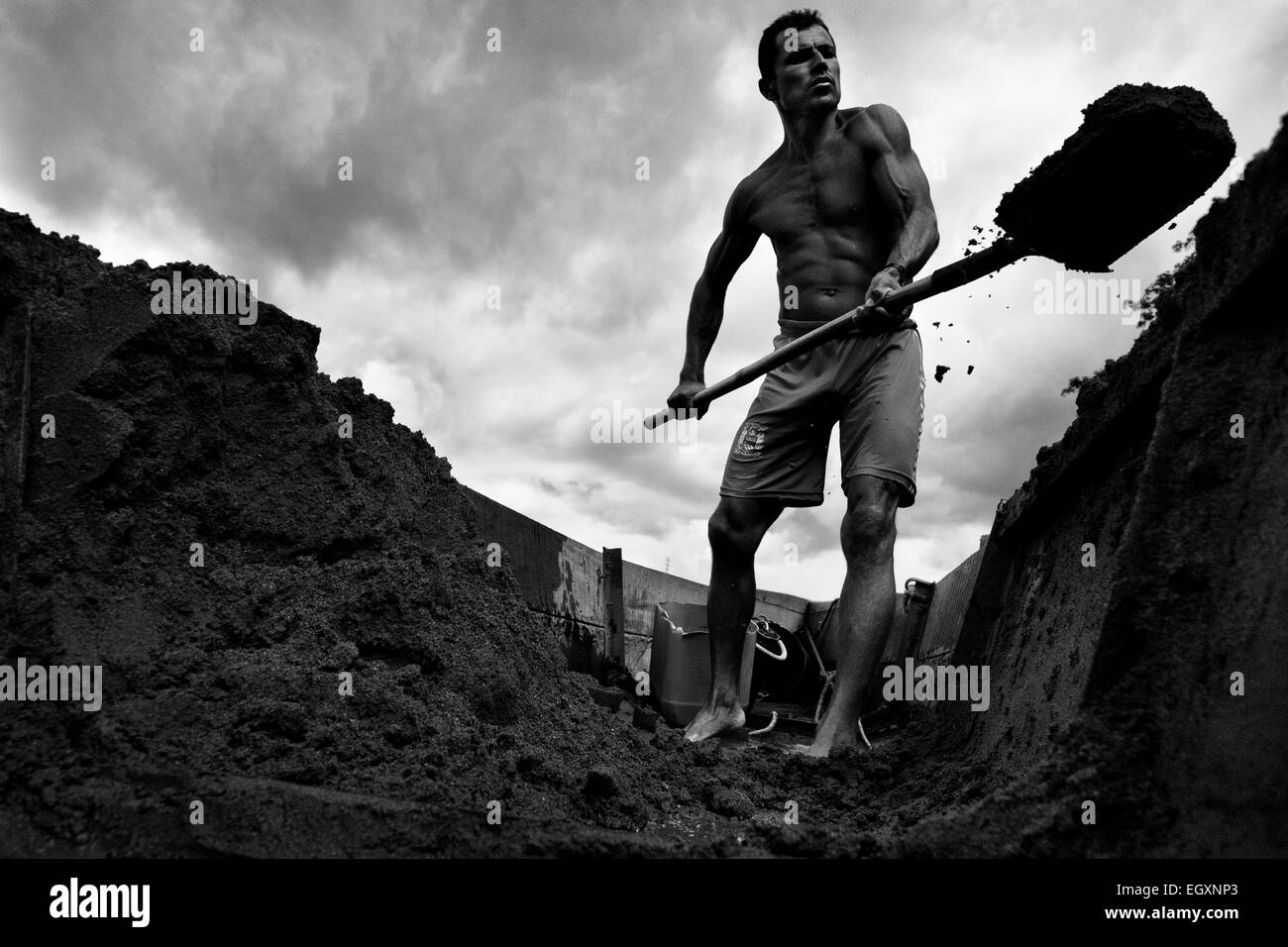 A Colombian sand miner unloads the extracted sand from his boat on the bank of the river La Vieja in Cartago, Colombia. Stock Photo