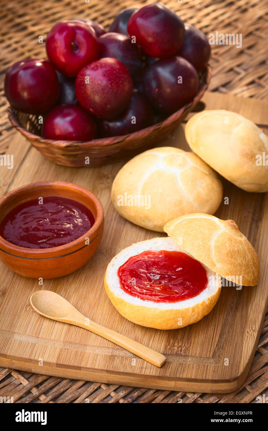 Plum jam spread on bun with plums in basket on wooden board photographed with natural light (Selective Focus) Stock Photo