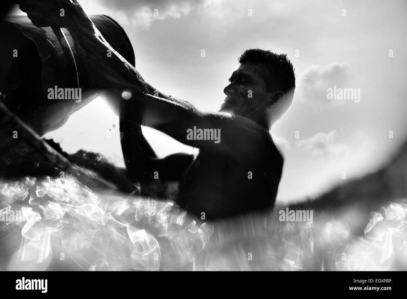 A Colombian sand miner unloads a bucket full of sand into his boat anchored in the middle of the river La Vieja in Cartago, Colombia. Stock Photo