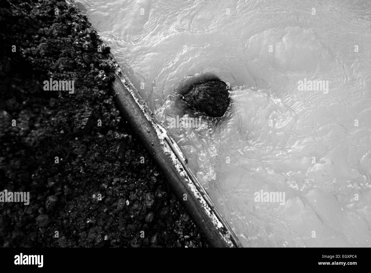 A top of the head of a Colombian sand miner, diving under the water to extract sand, seen in of the river La Vieja in Cartago, Colombia. Stock Photo