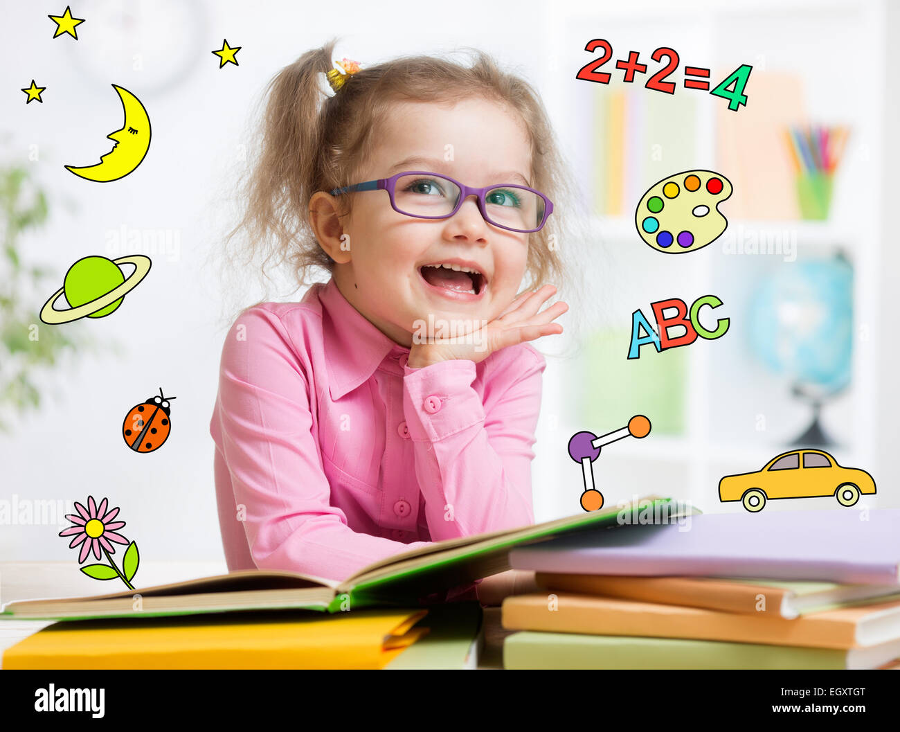 Funny smart kid in glasses reading book in kindergarten Stock Photo