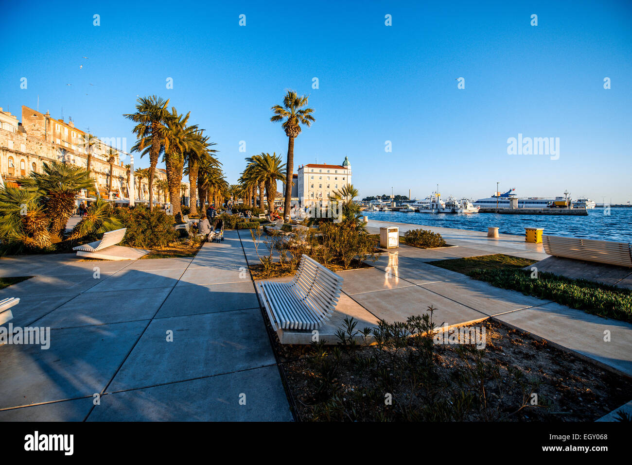 Split's promenade with benches, palms and sea in the evening in Croatia Stock Photo