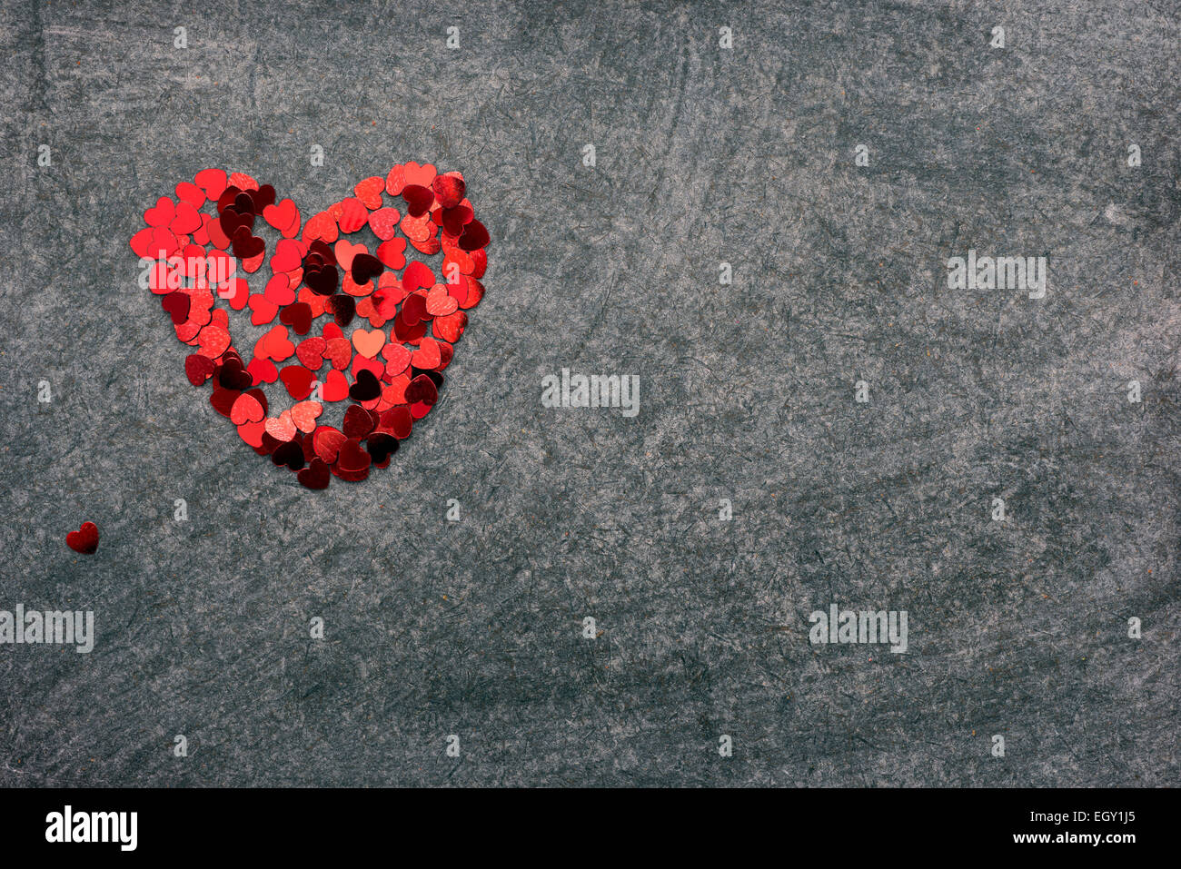 heart figure made from red confetti pieces on blackboard Stock Photo
