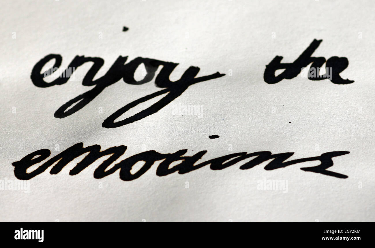words enjoy the emotions in italics by quill pen Stock Photo