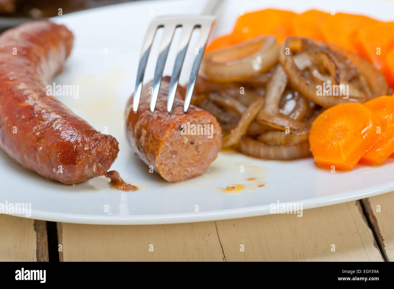 beef sausages cooked on iron skillet with carrot and onion Stock Photo