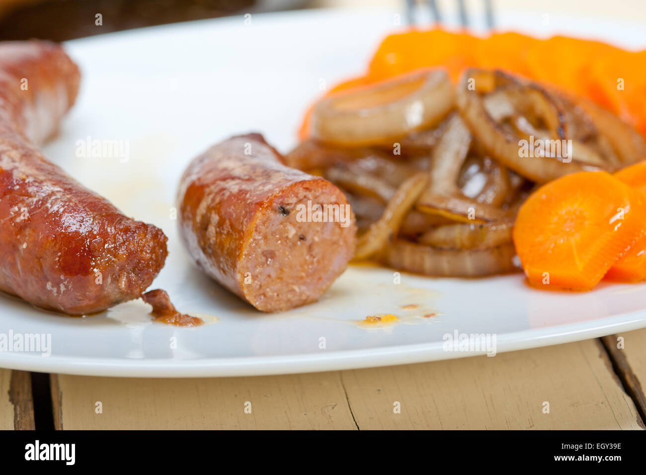 beef sausages cooked on iron skillet with carrot and onion Stock Photo