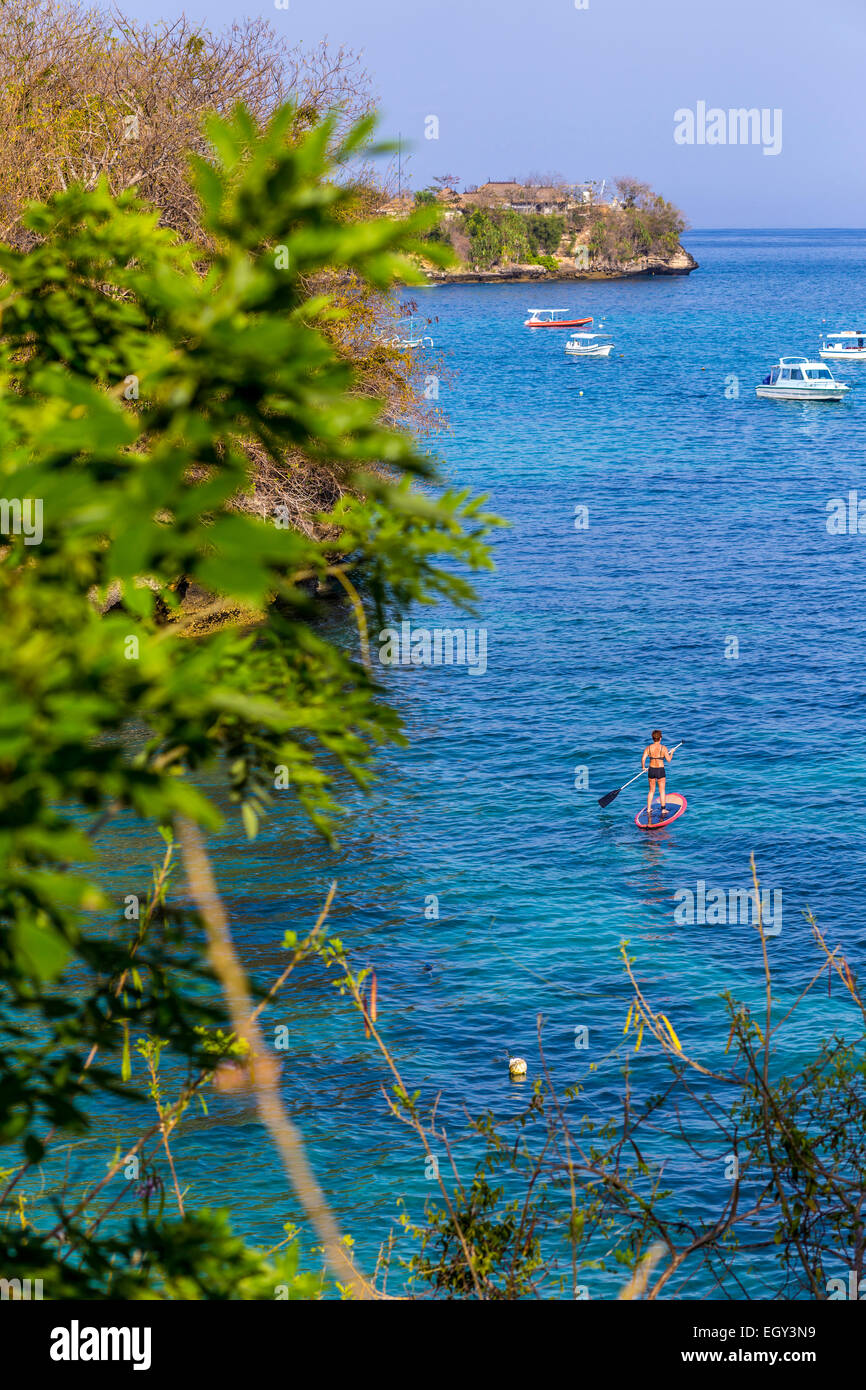 Woman travels by SUP at coastline of Nusa Lembongan and Nusa Ceningan islands, Indonesia. Stock Photo