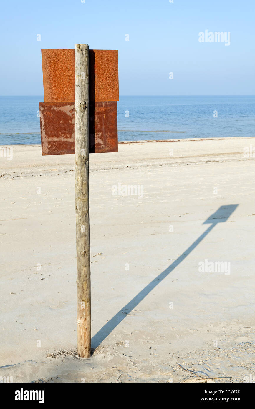 Rusty board sign on wooden post on a beach. Stock Photo