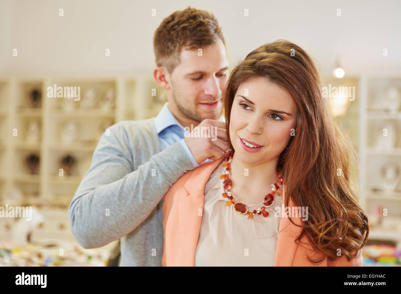 Salesman helping woman in jewelry store fitting a necklace Stock Photo