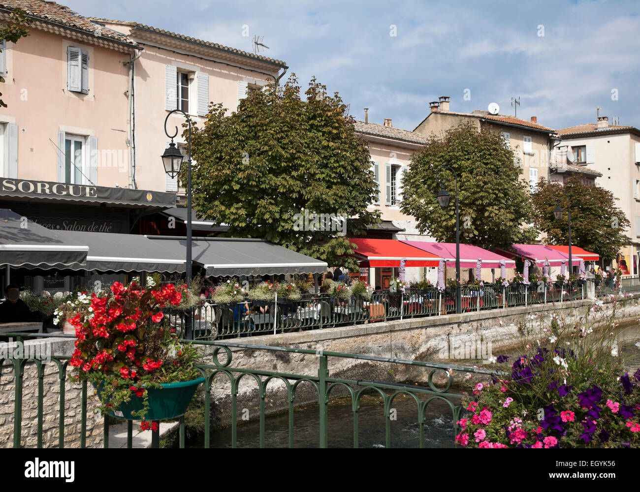 The brightly colored awnings of outdoor cafes line the edge of the Sorgue River in the heart of L'Isle-sur-la-Sorgue, Provence. Stock Photo