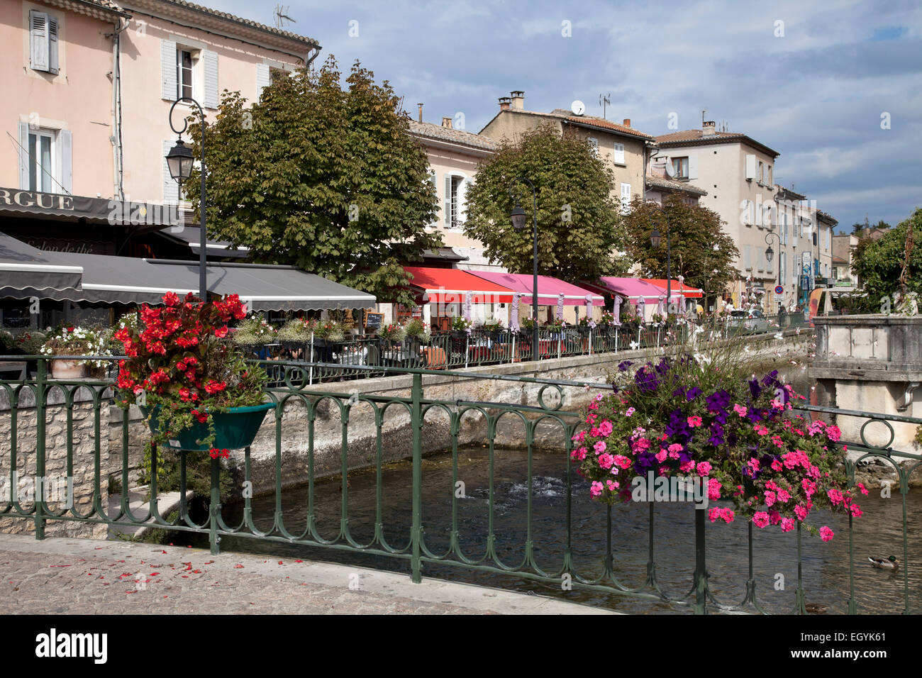 The brightly colored awnings of outdoor cafes line the edges of the Sorgue River in the heart of L'Isle-sur-la-Sorgue, Provence. Stock Photo