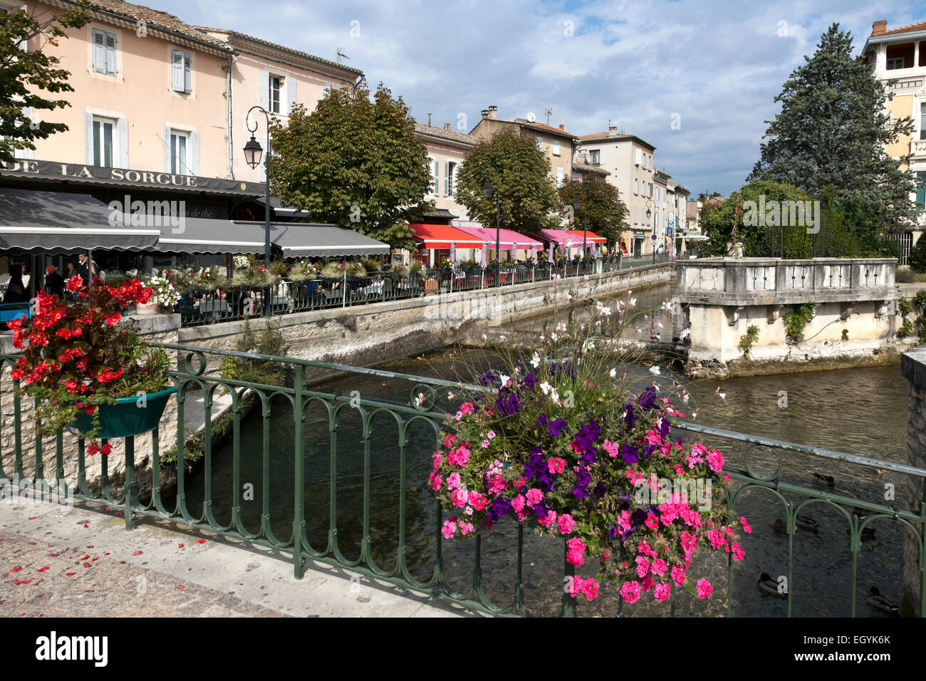 Brightly colored awnings of outdoor cafes line the edges of the Sorgue River in  the heart of L'Isle-sur-la-Sorgue, Provence Stock Photo