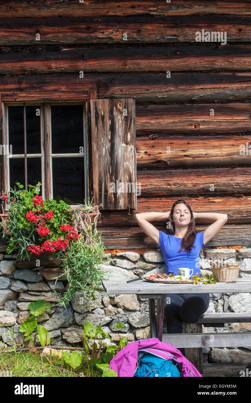 Austria, Altenmarkt-Zauchensee, young woman realxing at alpine cabin Stock Photo