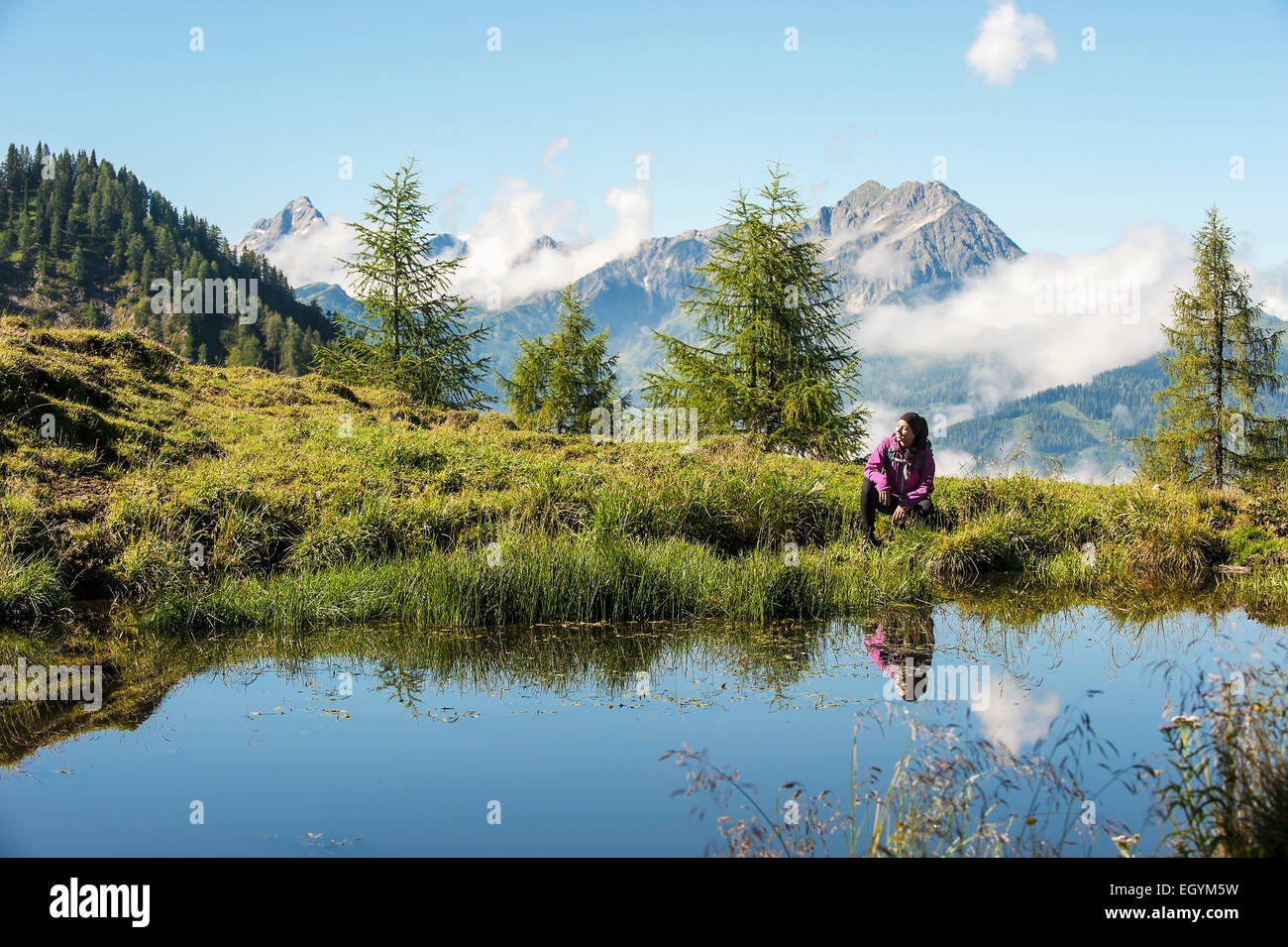 Austria, Altenmarkt-Zauchensee, young woman hiking in alpine landscape Stock Photo