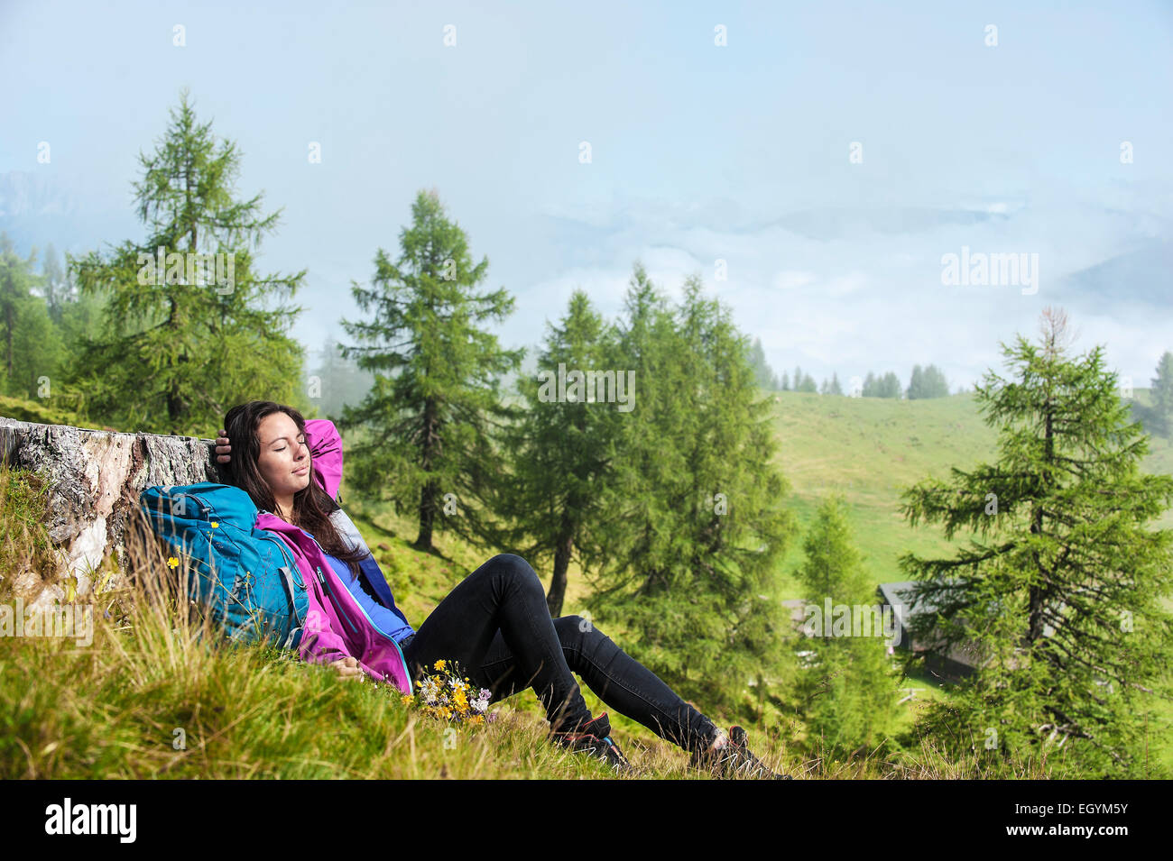 Austria, Altenmarkt-Zauchensee, young woman lying on alpine meadow Stock Photo