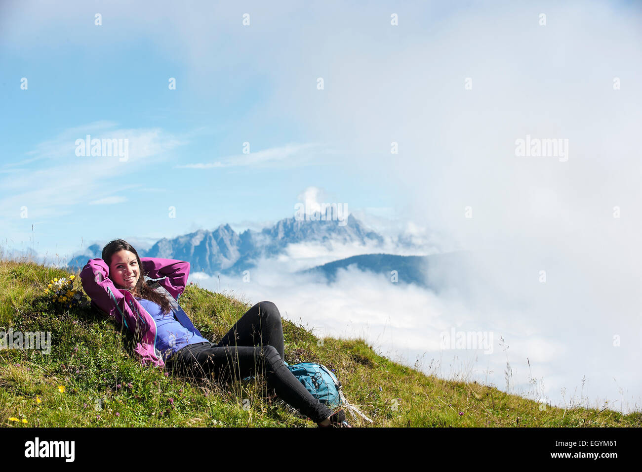 Austria, Altenmarkt-Zauchensee, young woman lying on alpine meadow Stock Photo