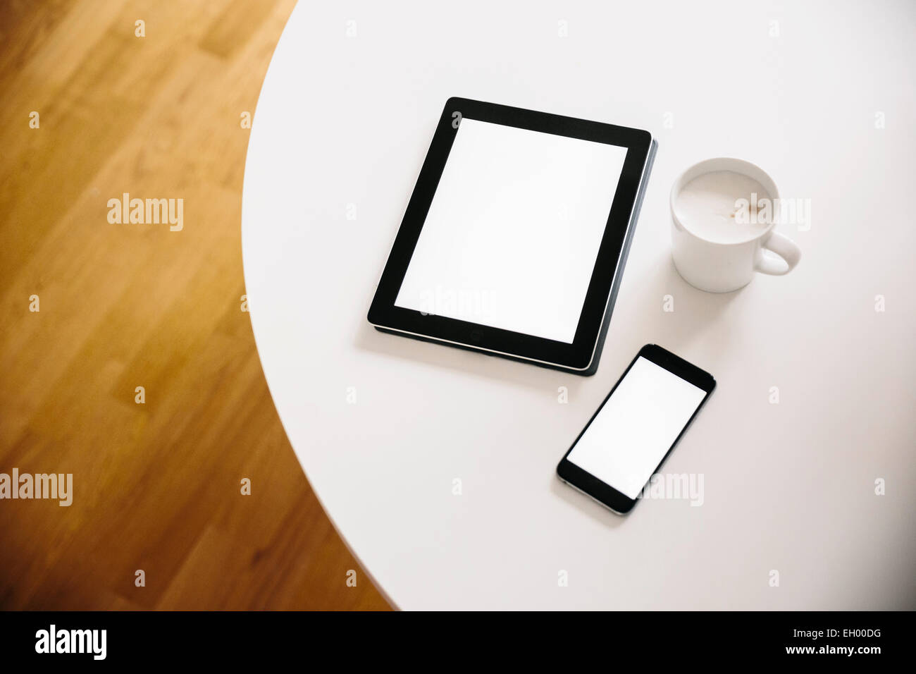 Tablet PC and smart phone with a cup of coffee on a white round table Stock Photo