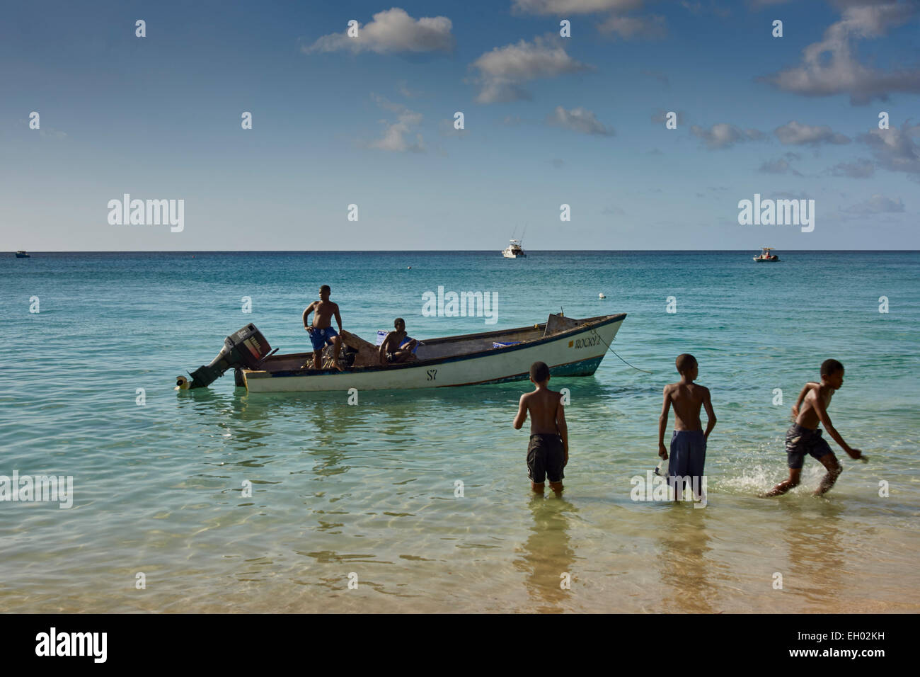 Barbados beach, fishing boat, boys in water Stock Photo