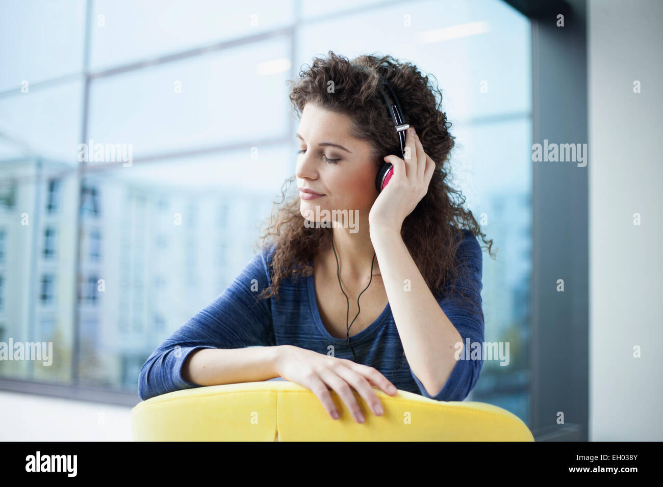 Young woman wearing headphones at the window Stock Photo