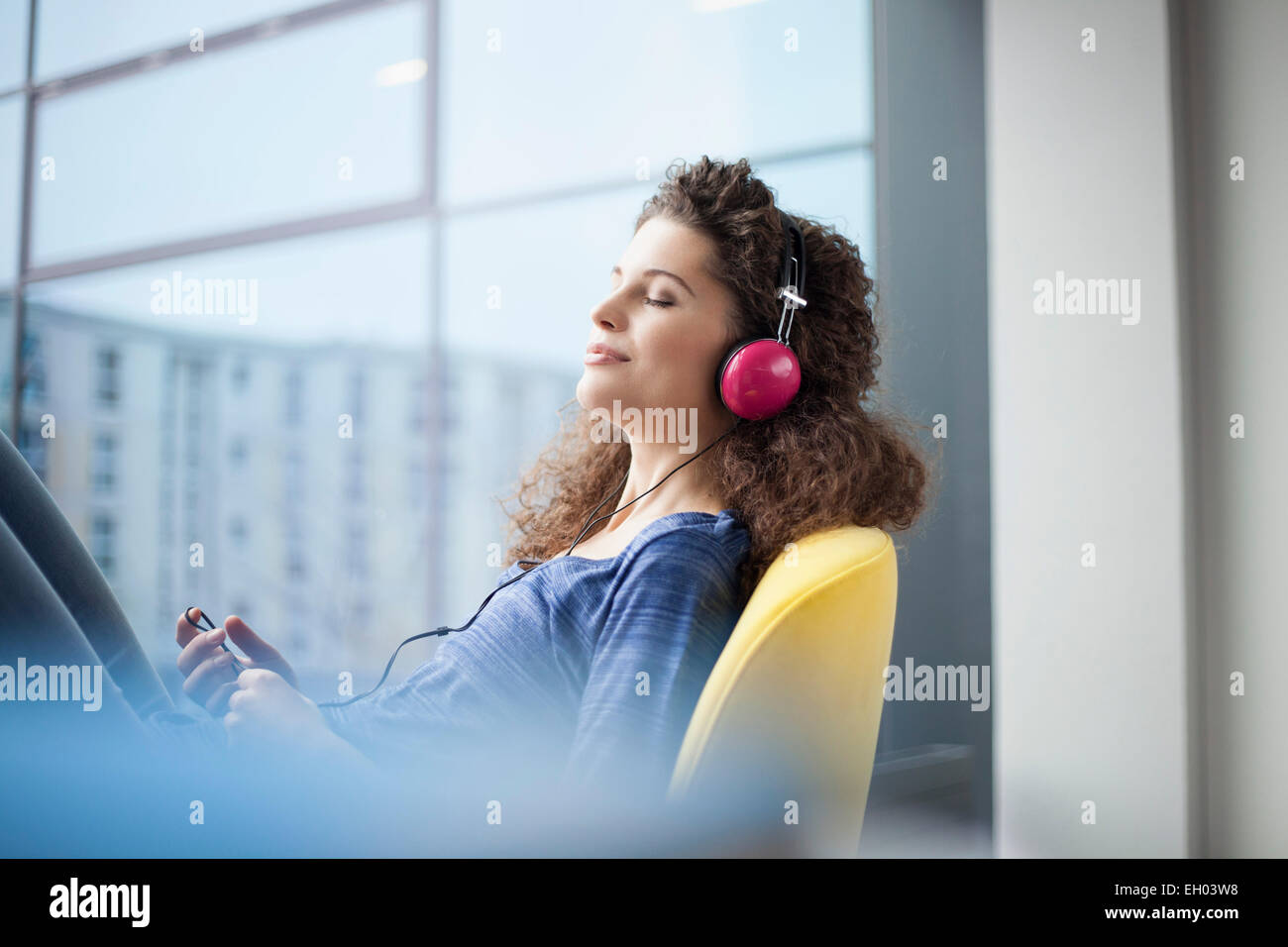 Young woman wearing headphones at the window Stock Photo