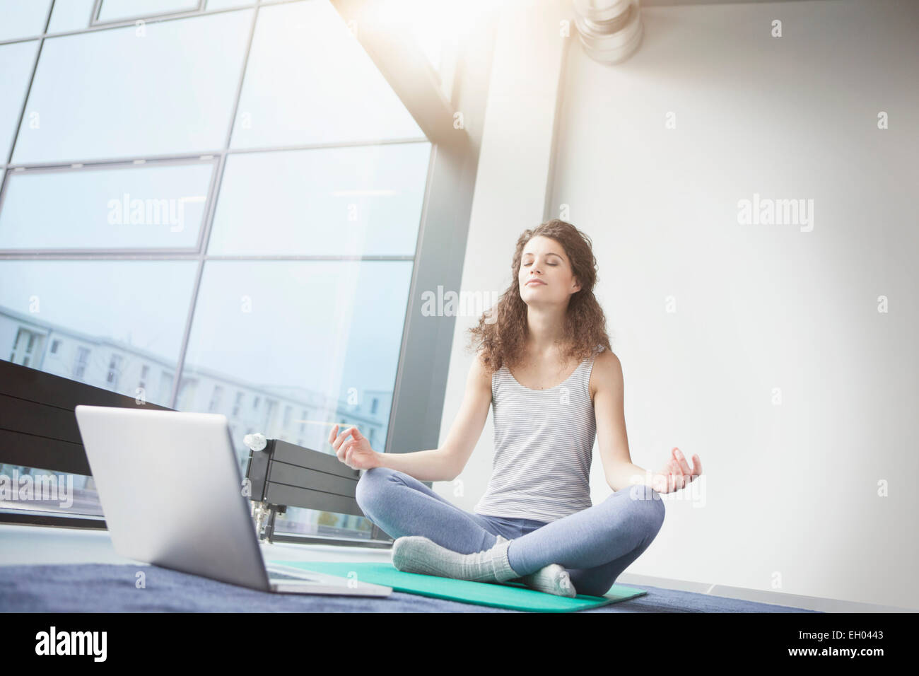 Woman doing yoga with laptop Stock Photo