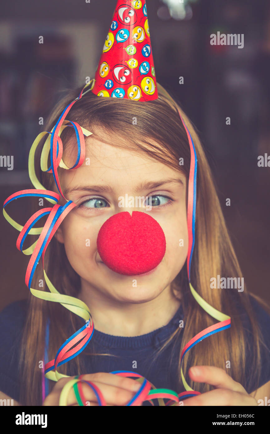 Cross-eyed girl with clown's nose, cap and streamer Stock Photo
